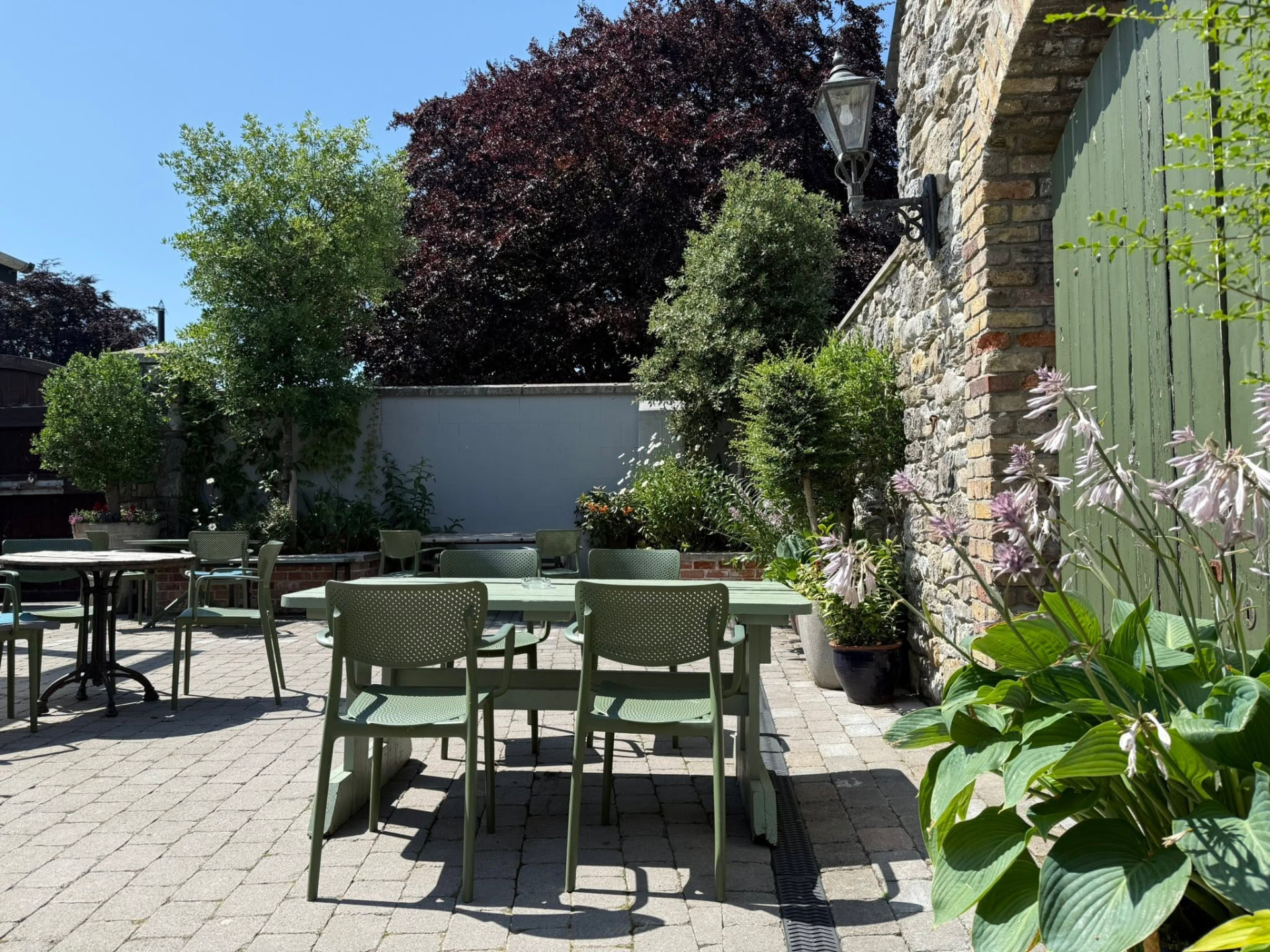 Green tables and chairs in the walled courtyard