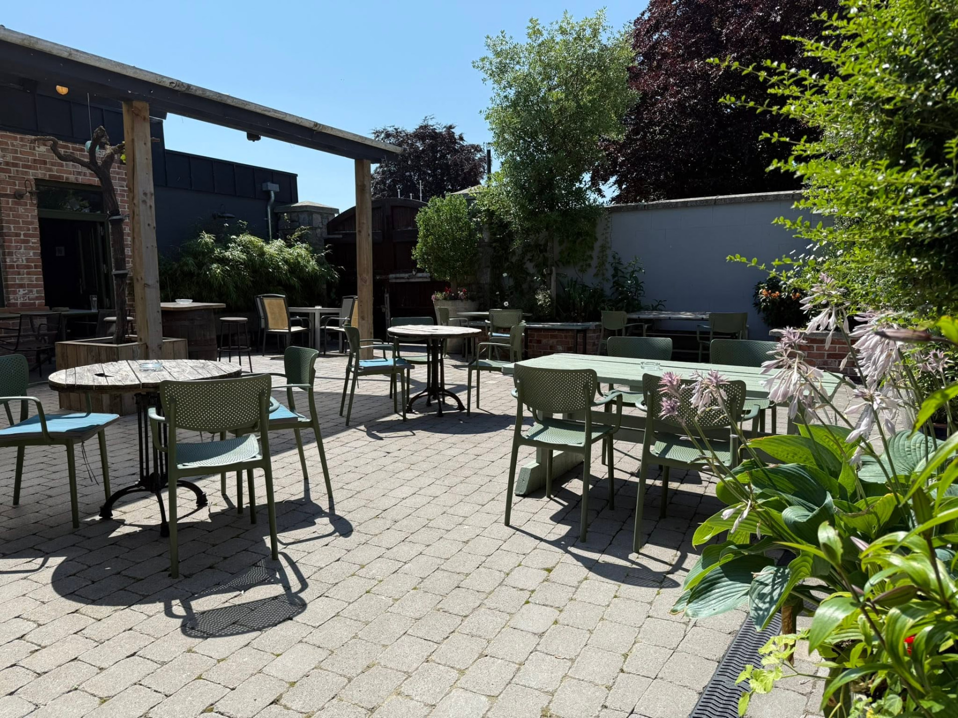 The sun-trap courtyard with green tables and chairs